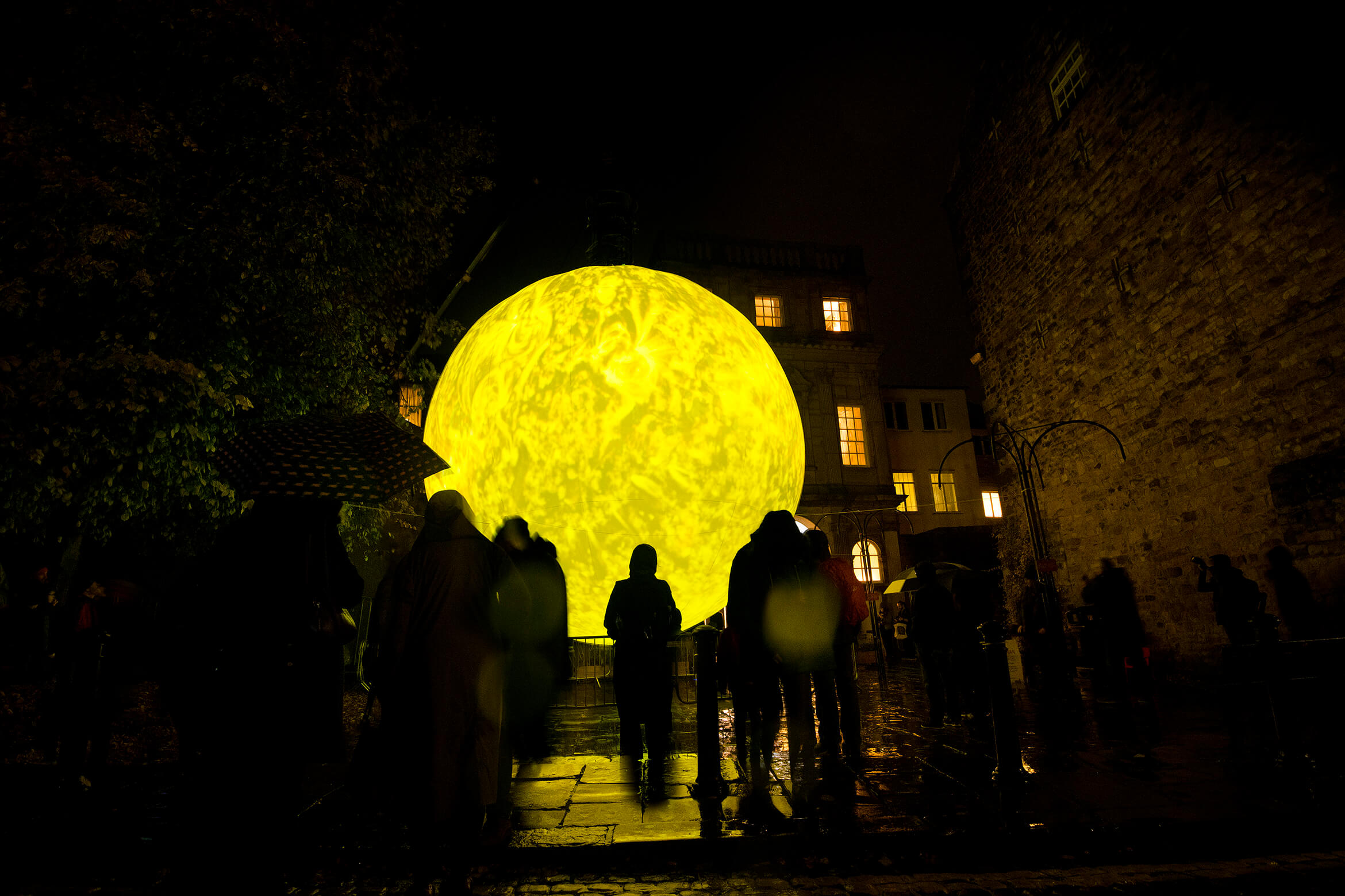 Photograph of SUN taken outside at night and showing in a group of people watching it